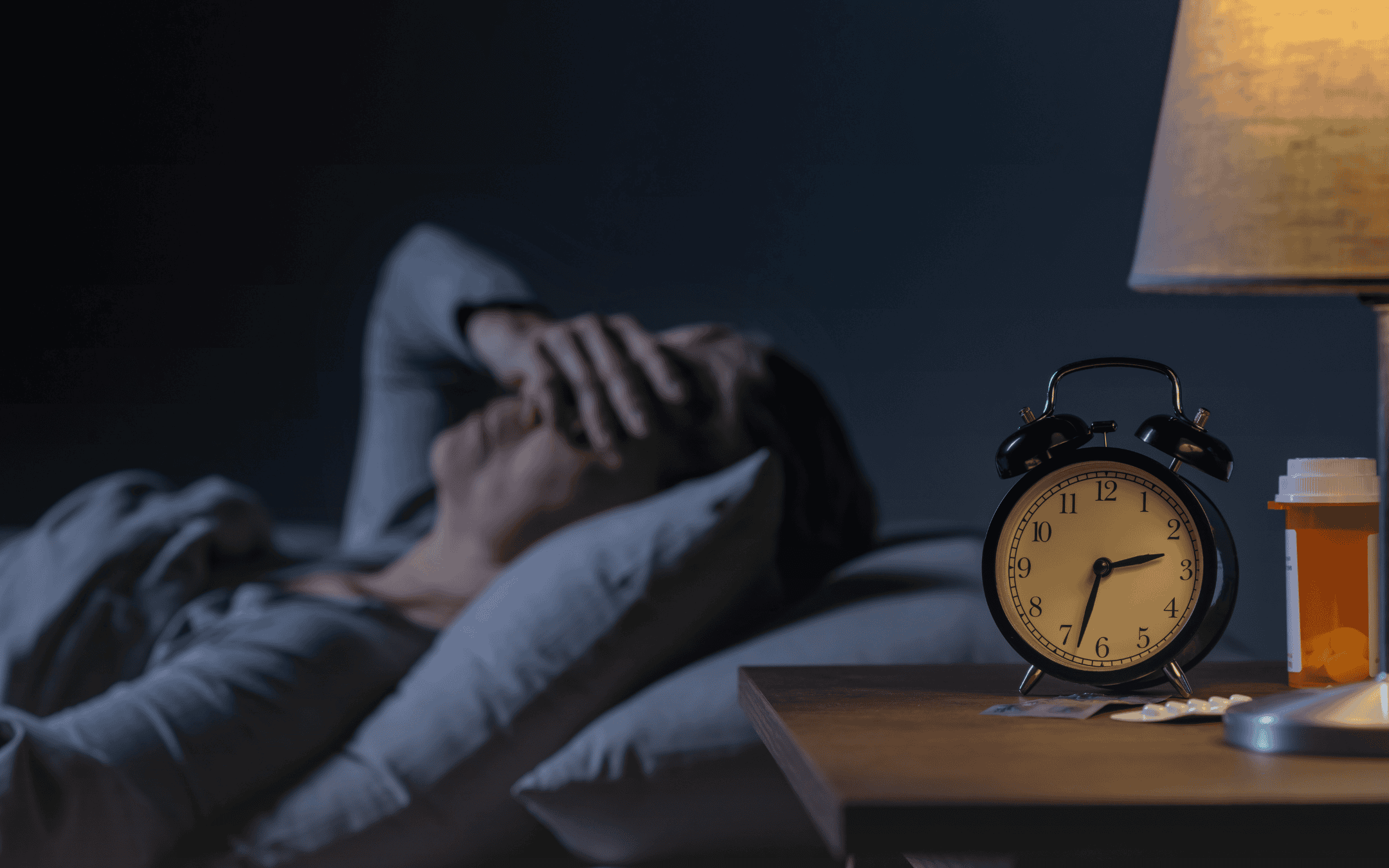 Elderly woman lying awake in bed in the middle of the night with hands over her eyes, indicating sleep problems, a common symptom of nutrient depletion due to stress and grief.